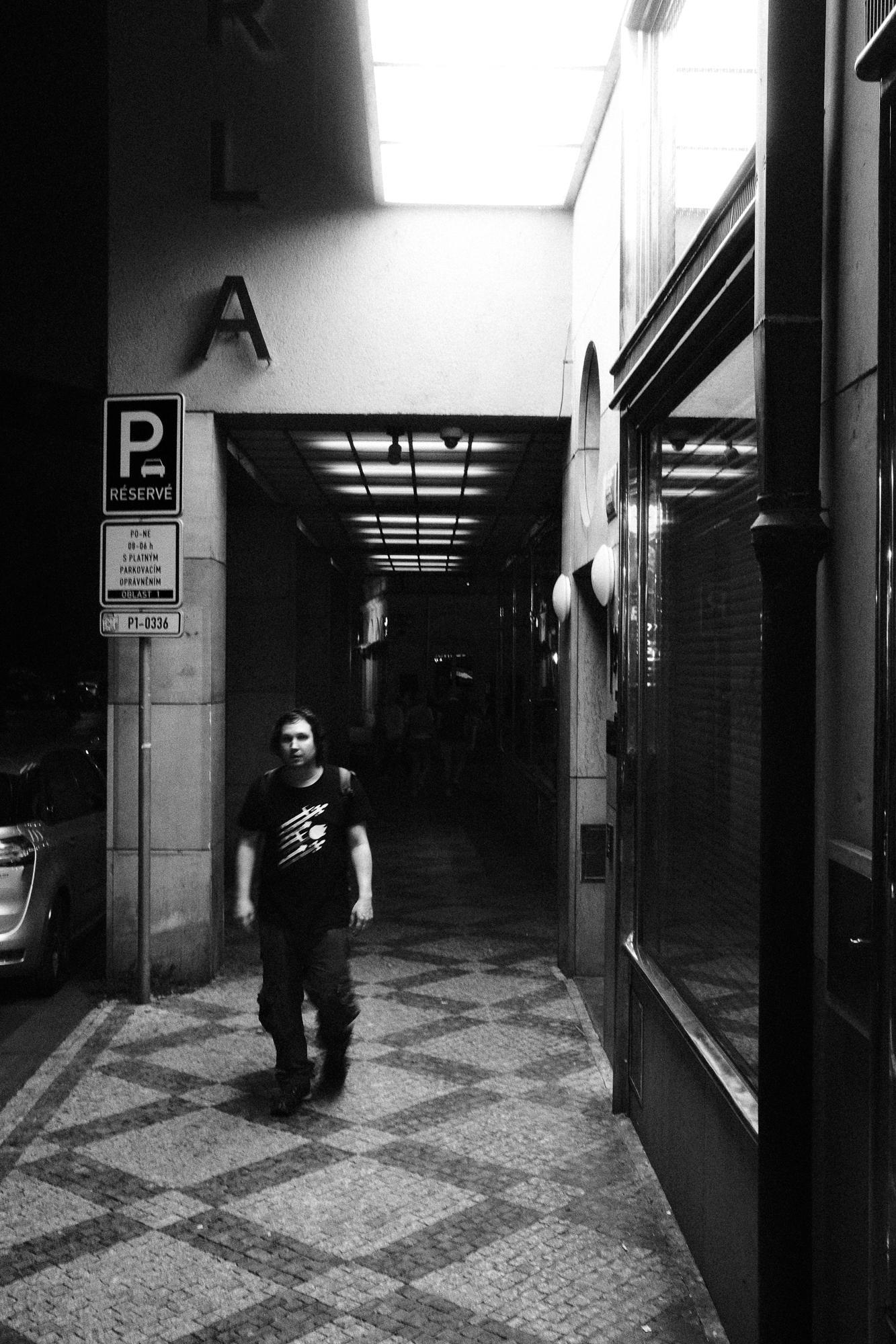 Muž kráča von z tmavého podchodu pod hotelom.