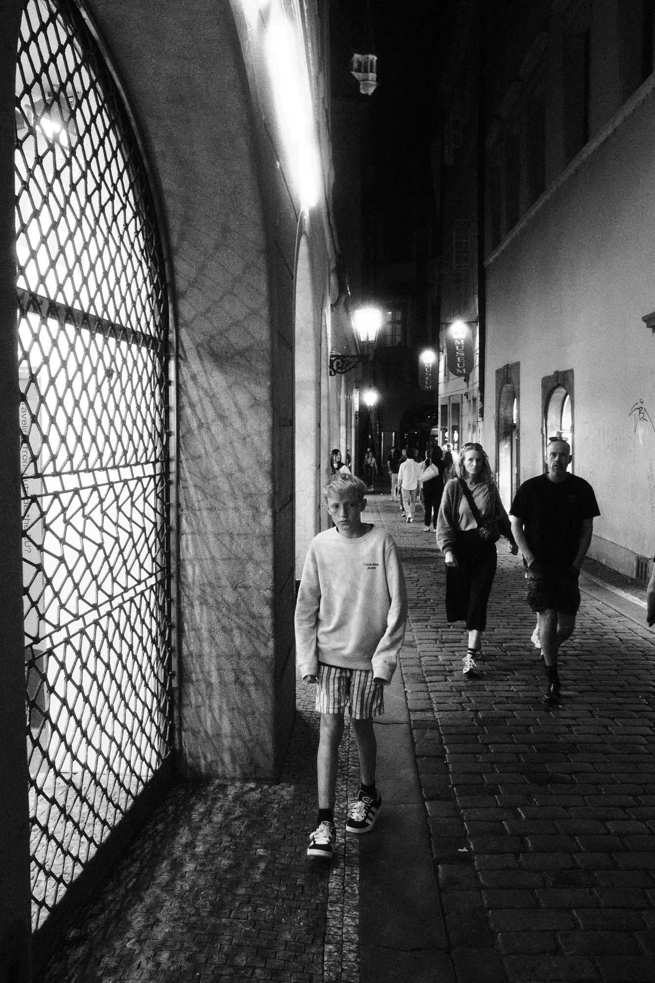 Čiernobiela fotografia nočnej uličky s dláždenou cestou.