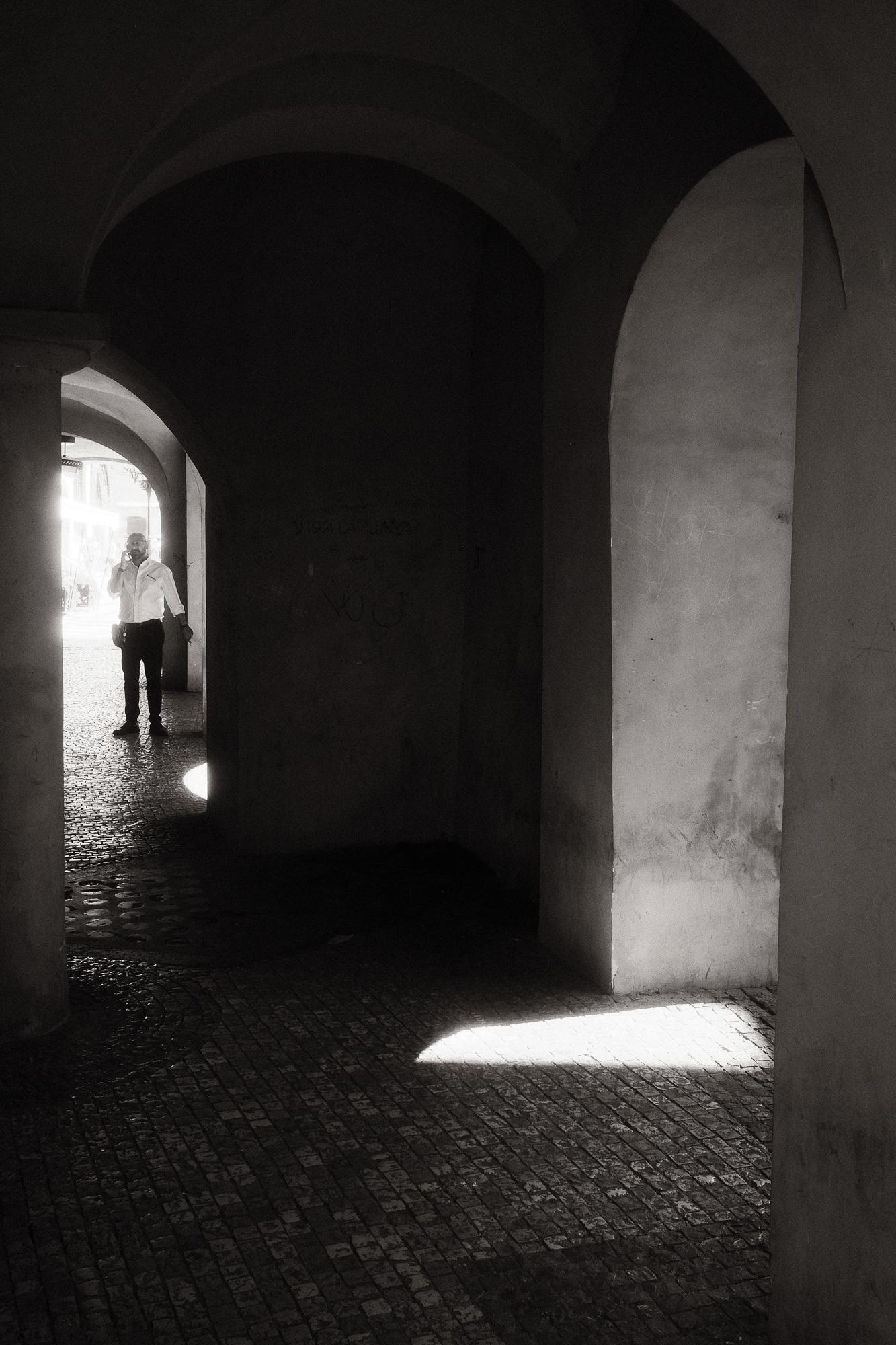 Čiernobiela fotografia muža telefonujúceho vo svetle.