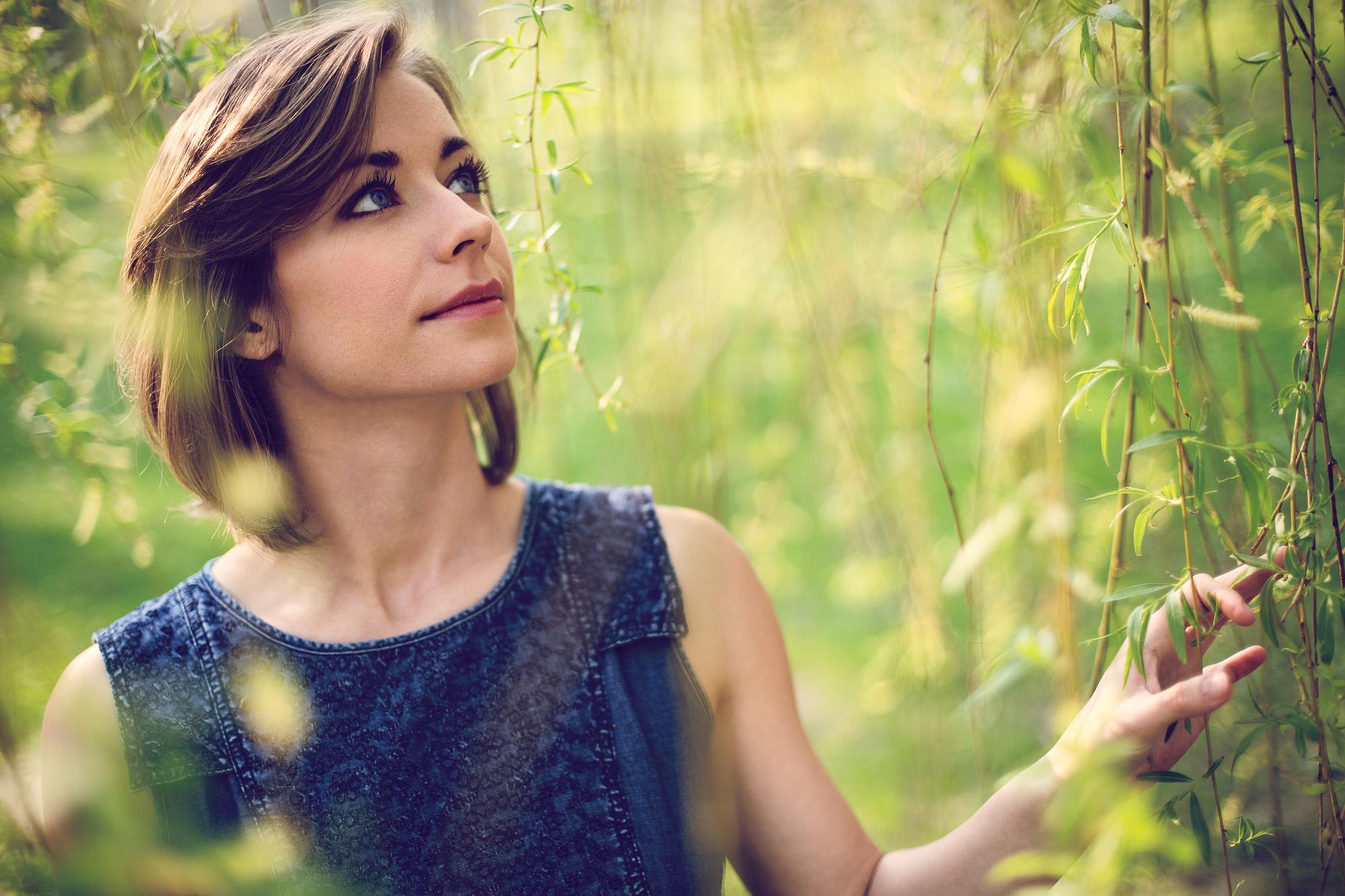 Portrét mladej ženy s krásnymi očami obklopenej listami vŕbi v jemnom svetle. V sade Janka Kráľa v Bratislave