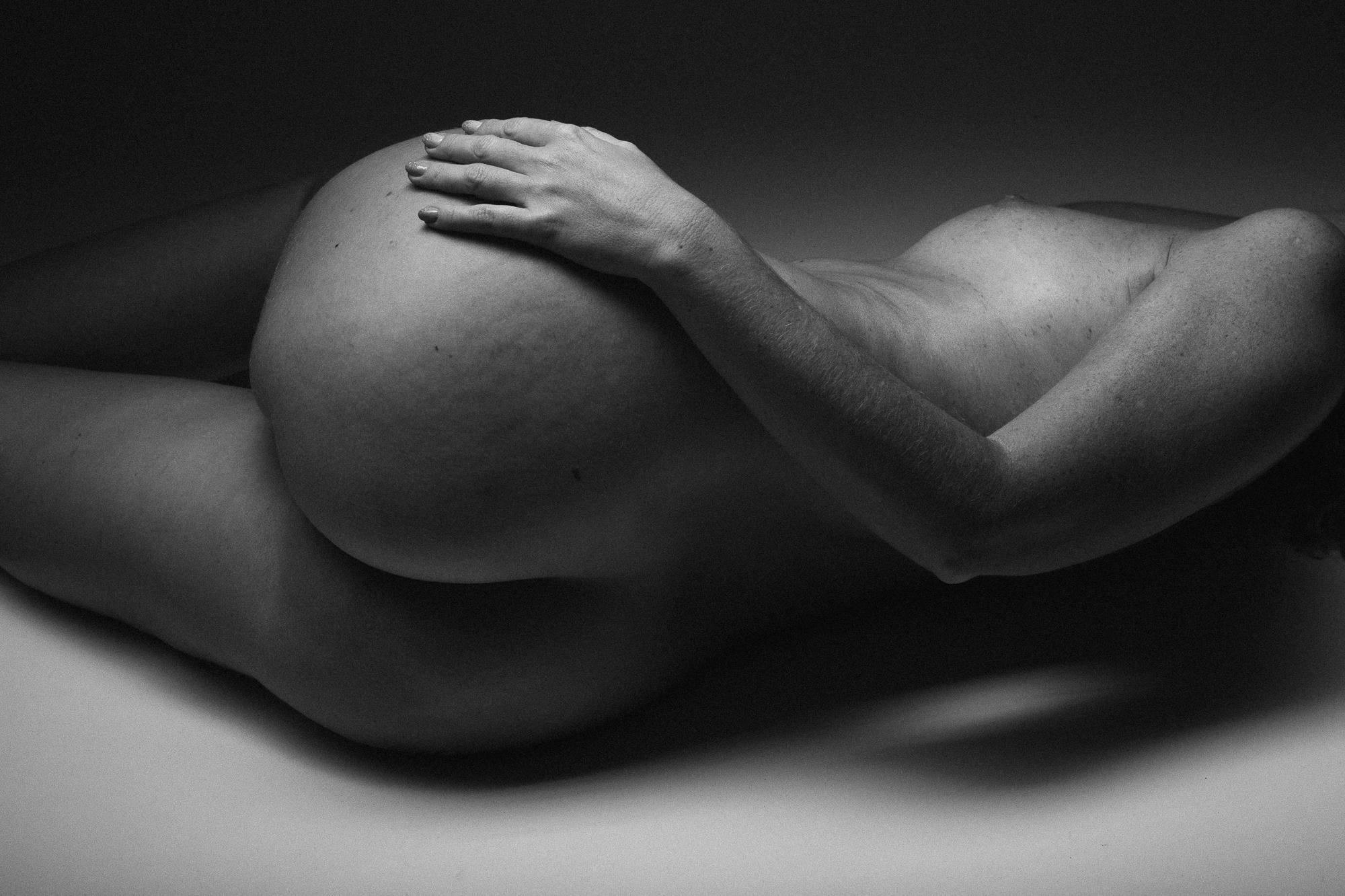 Čierno-biely umelecký akt zachytávajúci intímnu pózu ženského tela, s dôrazom na jemné krivky a textúru pokožky. Ateliér Pezinok.