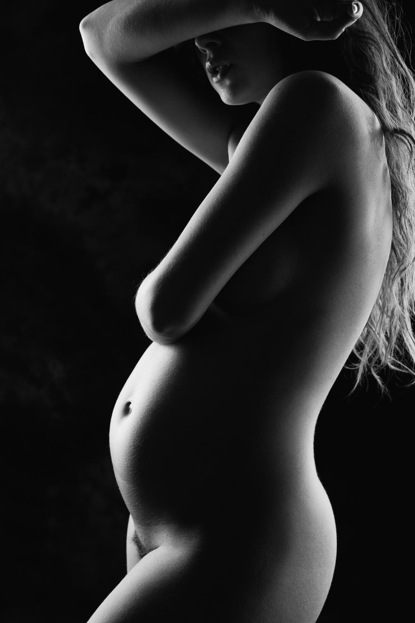 Čierno-biely umelecký akt tehotnej ženy zobrazujúci ženskú siluetu s jemným osvetlením, zvýrazňujúcim krivky tela. Bratislava.