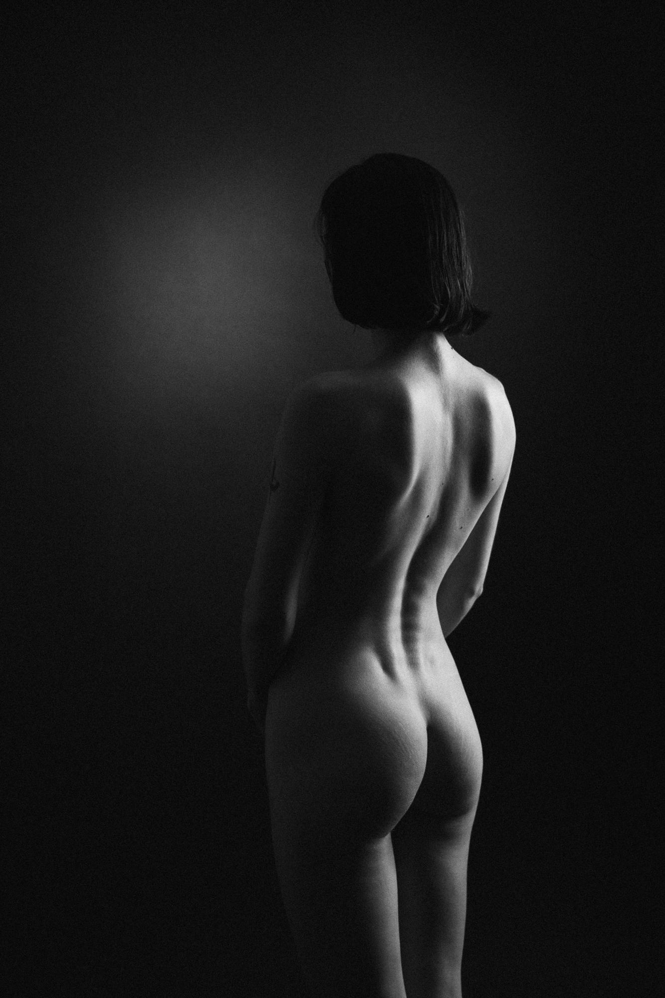 Čierno-biely umelecký akt zachytávajúci ženskú postavu zozadu so zameraním na elegantné krivky chrbta a pozadia. Ateliér Pezinok.