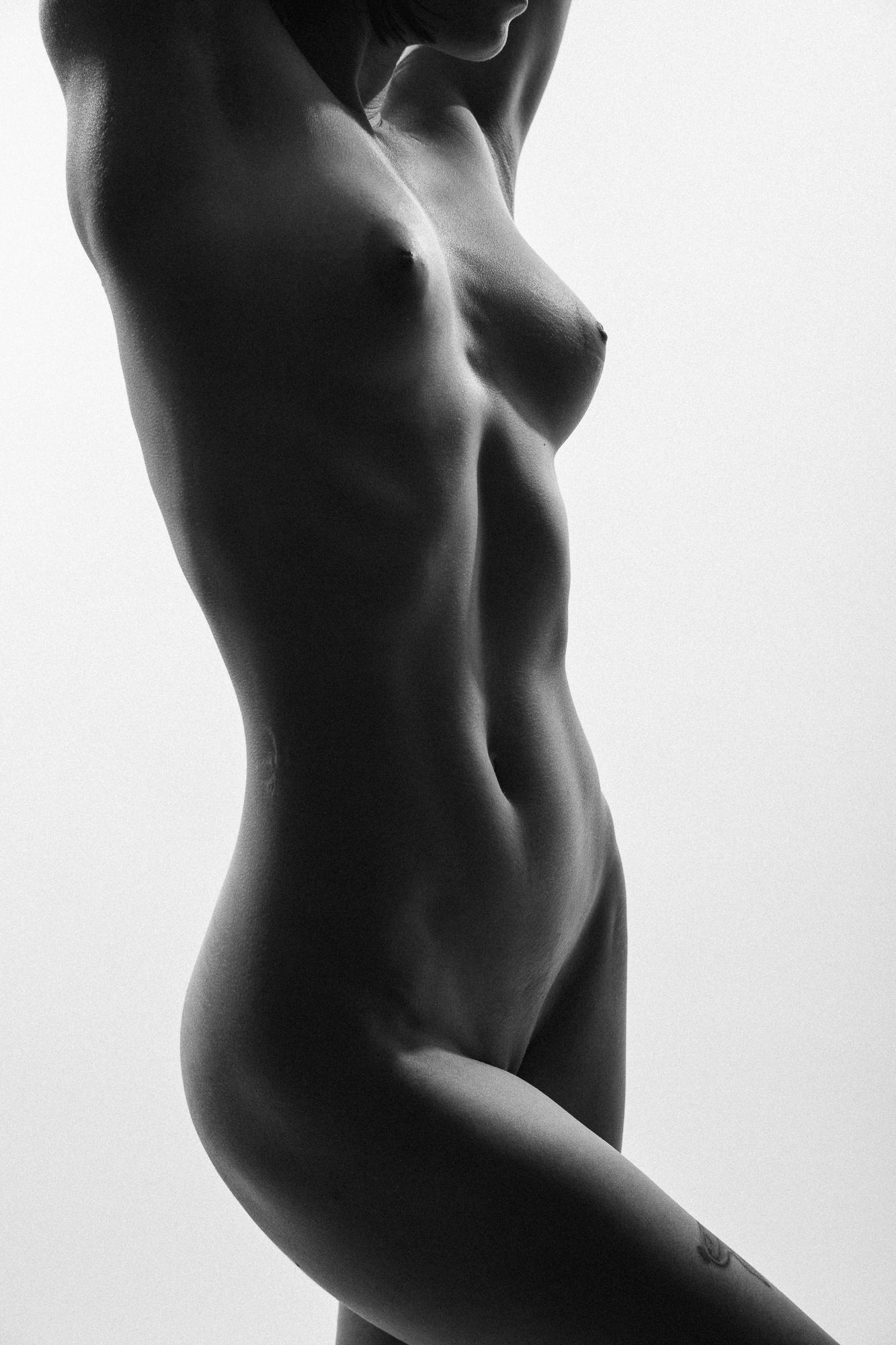 Čierno-biely umelecký akt ženy, ktorý zobrazuje elegantné línie tela a jemné textúry pokožky. Ateliér Pezinok.