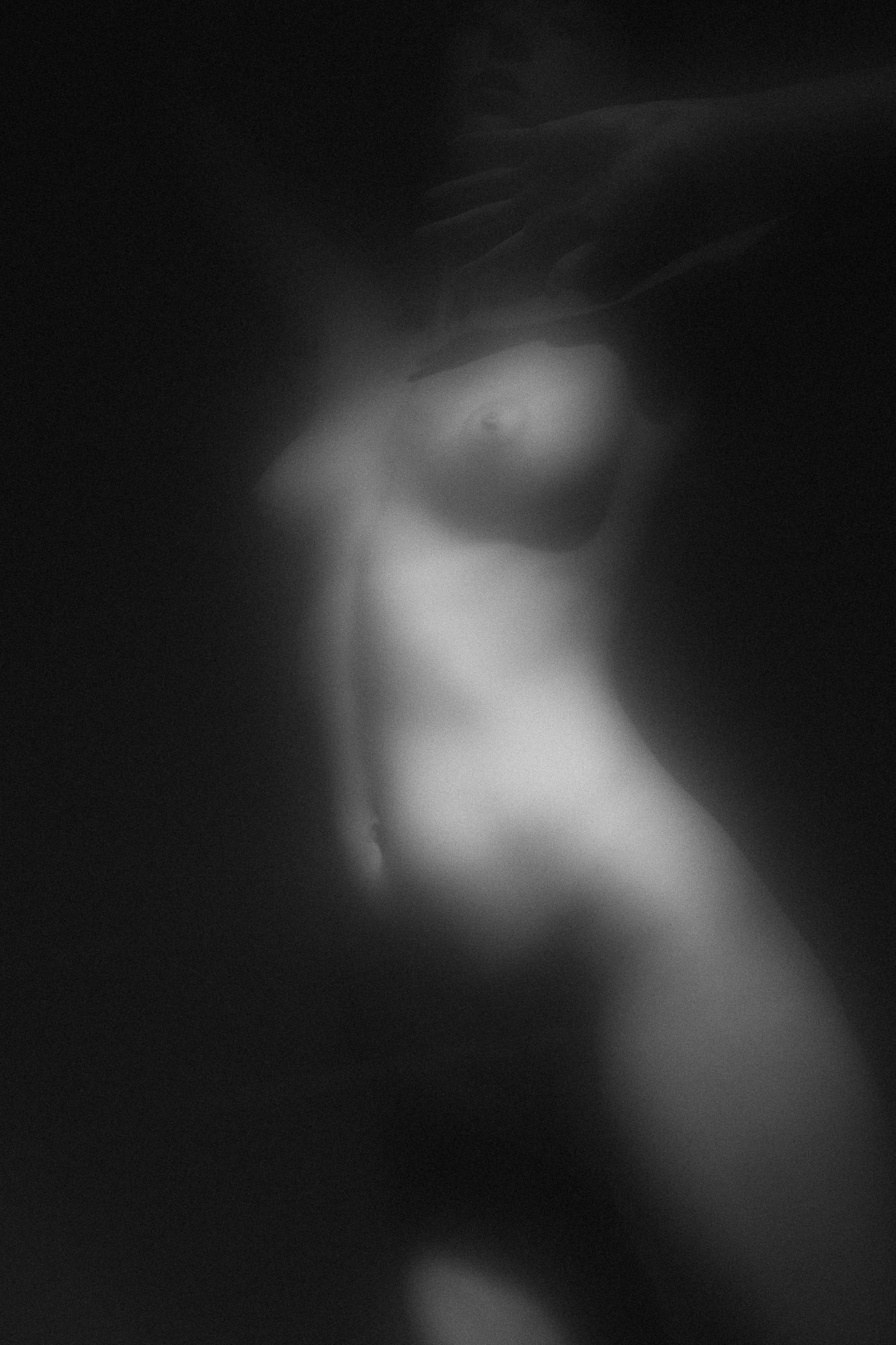 Čierno-biely umelecký akt zachytáva jemnú siluetu ženského tela v mäkkom svetle, vytvárajúc dojem éterickej krásy. Ateliér Pezinok.