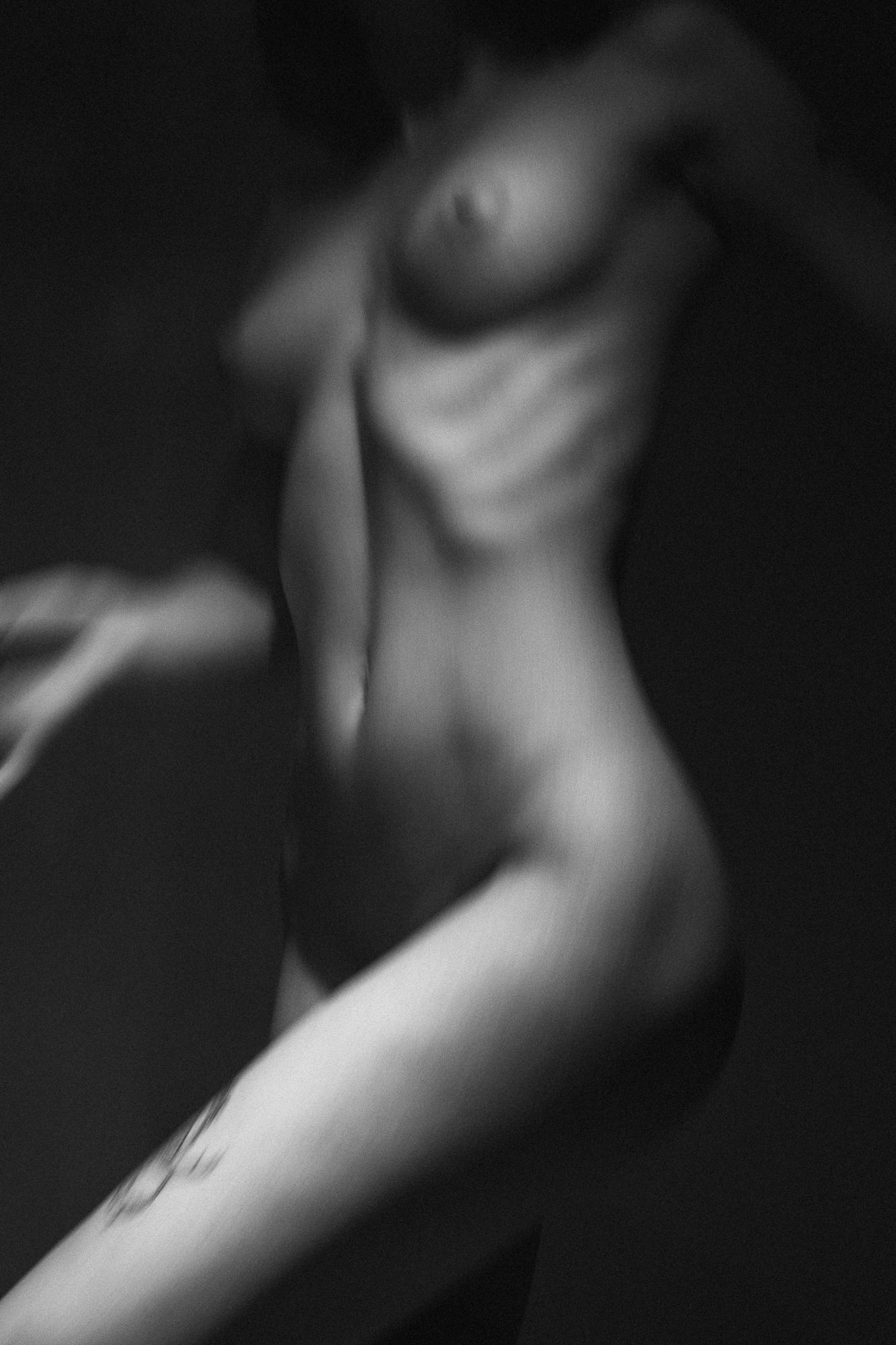 Čierno-biely umelecký akt s jemným osvetlením, ktorý zdôrazňuje krivky tela v dynamickej póze. Ateliér Pezinok.