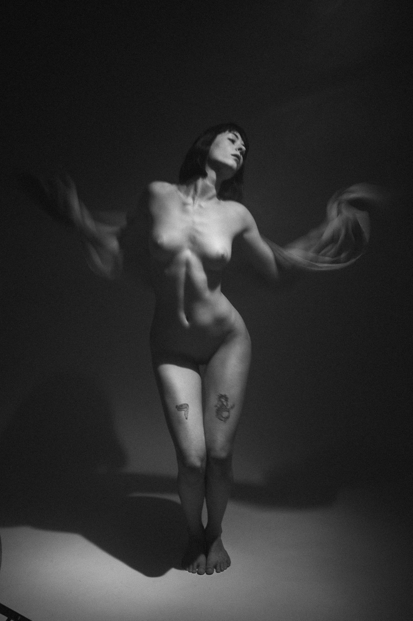 Intímny čierno-biely umelecký akt zachytávajúci postavu ženy v pohybe zvýraznenom rozmazanou látkou v rukách. Ateliér Pezinok.
