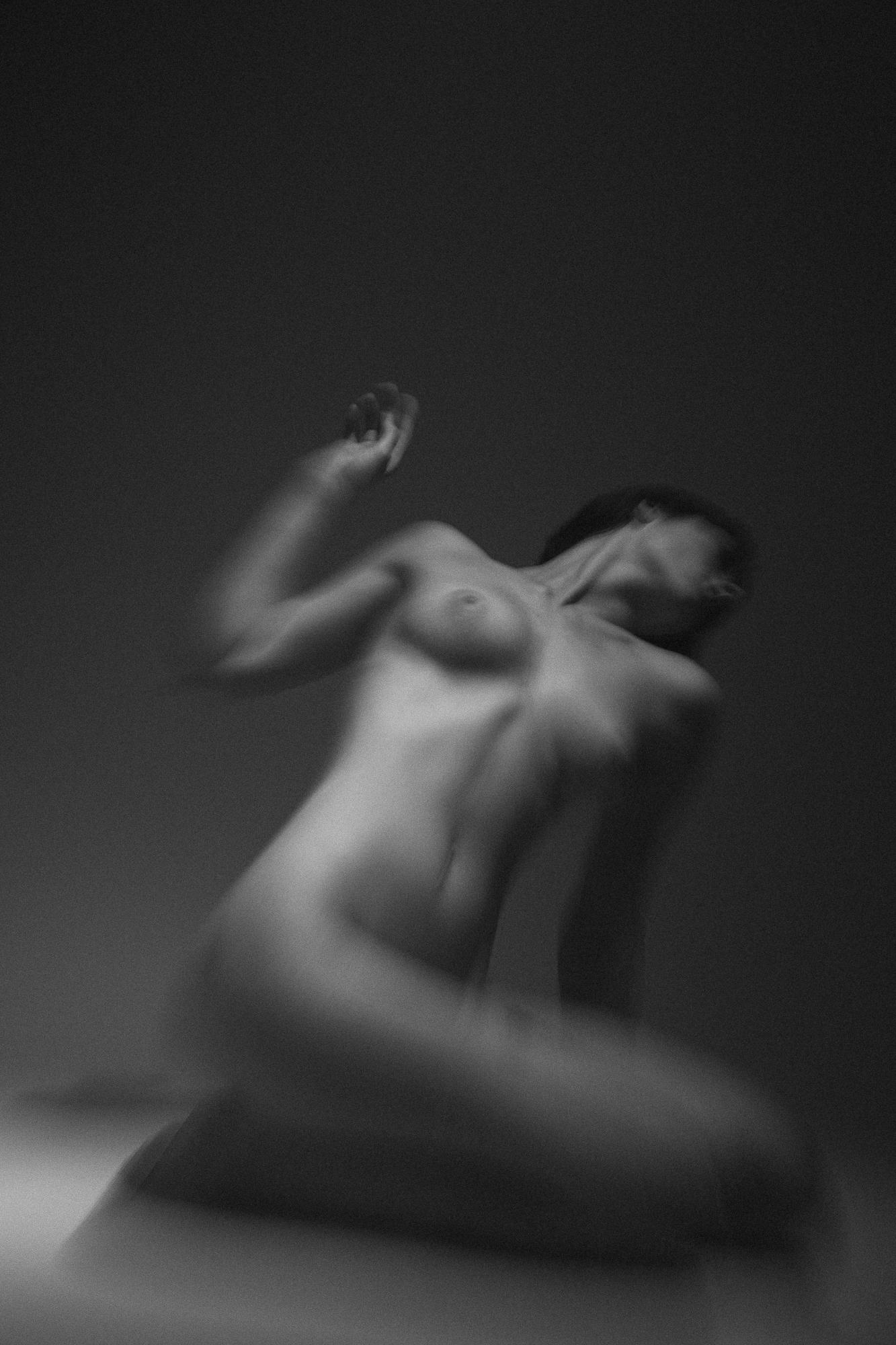 Čierno-biely umelecký akt zachytáva jemné krivky zmyselne pôsobiacej rozmazanej ženskej postavy na tmavom pozadí. Ateliér Pezinok.