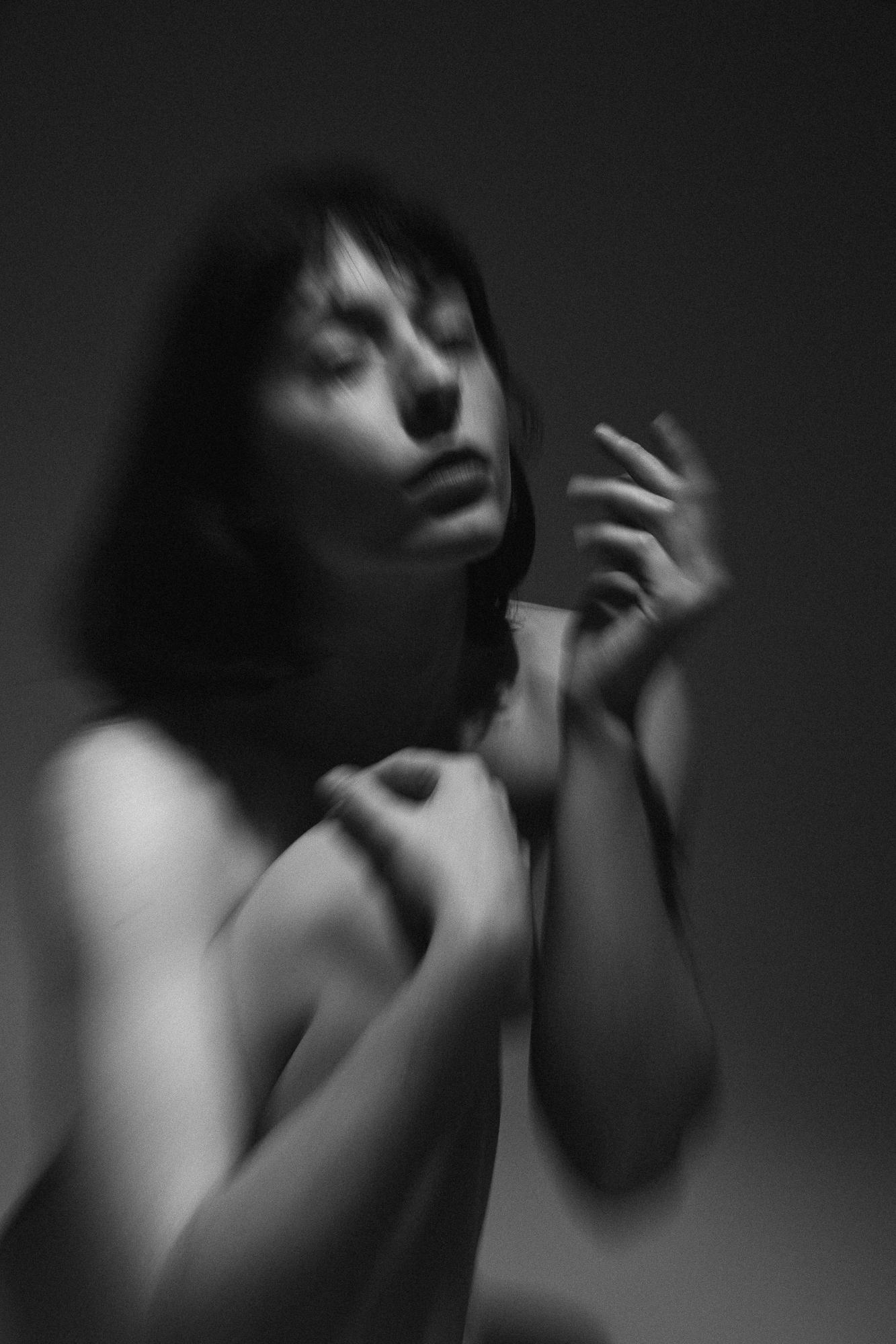 Rozmazaný čiernobiely portrét mladej ženy so zavretými očami a emotívnym výrazom. Ateliér Pezinok.